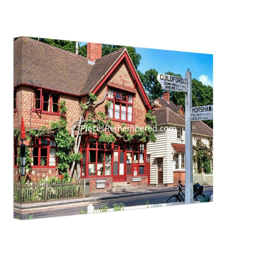 1950s Abinger Hammer Post Office in Surrey, England, with its traditional fingerpost sign and picturesque village buildings, prepared in a clean photographic style from a genuine vintage color photograph.
