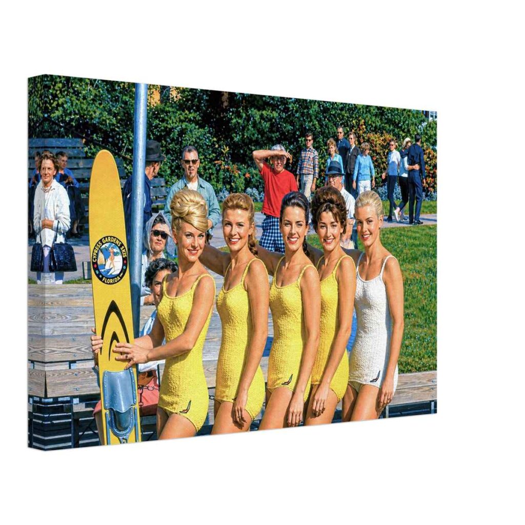 Painterly 1960s view of five female water skiers at Cypress Gardens, Florida, wearing coordinated swimsuits and posing beside a yellow Cypress Gardens water ski.