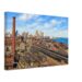 Painterly 1950s view of the Detroit riverfront from the Ambassador Bridge, with railroad yards, freight cars, industrial buildings, downtown skyline and the Detroit River.