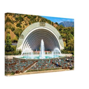 Painterly 1950s view of the Hollywood Bowl in California, with fountains in front of the amphitheater, rows of seats, visitors and hills behind the stage.
