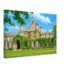 Painterly 1950s view of St John’s College in Oxford, England, with ivy-covered historic college buildings, Gothic towers, lawns, flower beds and blue sky.